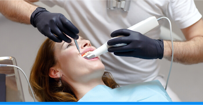 A dentist holding an intraoral camera in a woman's mouth
